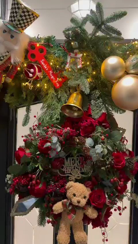 A detail of a lit indoor garland with gold bells, a nutcracker figure and red roses.