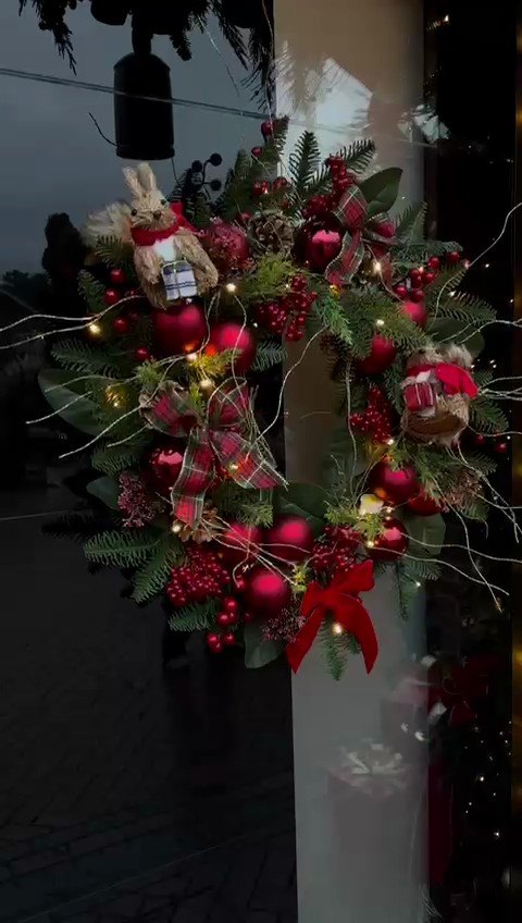 A large door wreath of fresh fir, red berries and burgundy baubles.